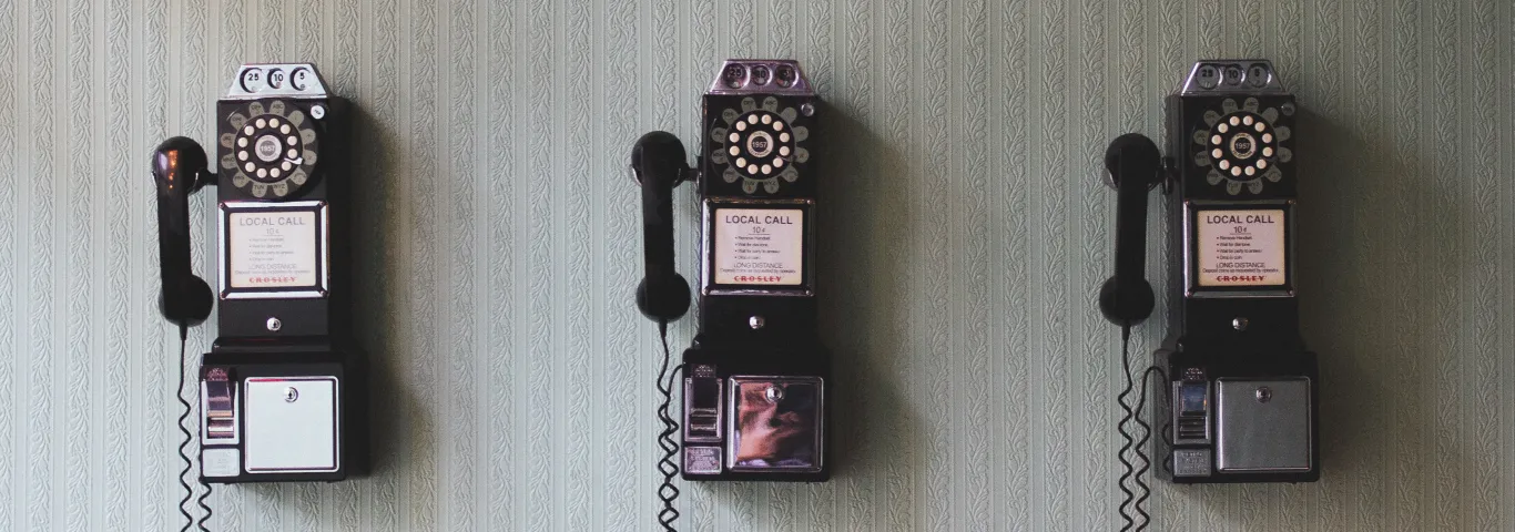 three rotary-dial pay phones on a wall